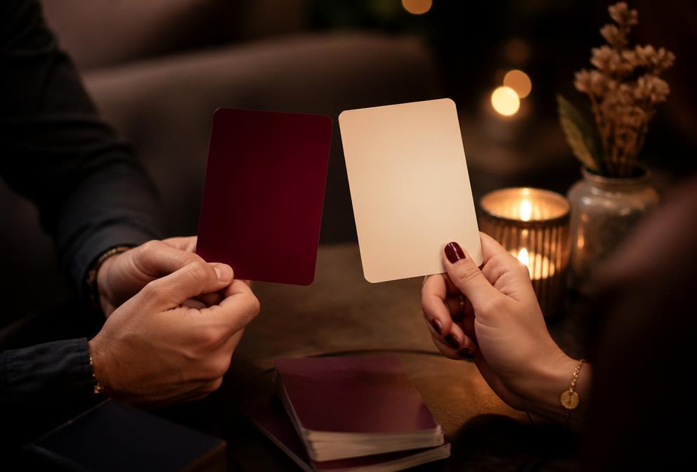 A couple holding 5Fs conversation cards over a candlelit table